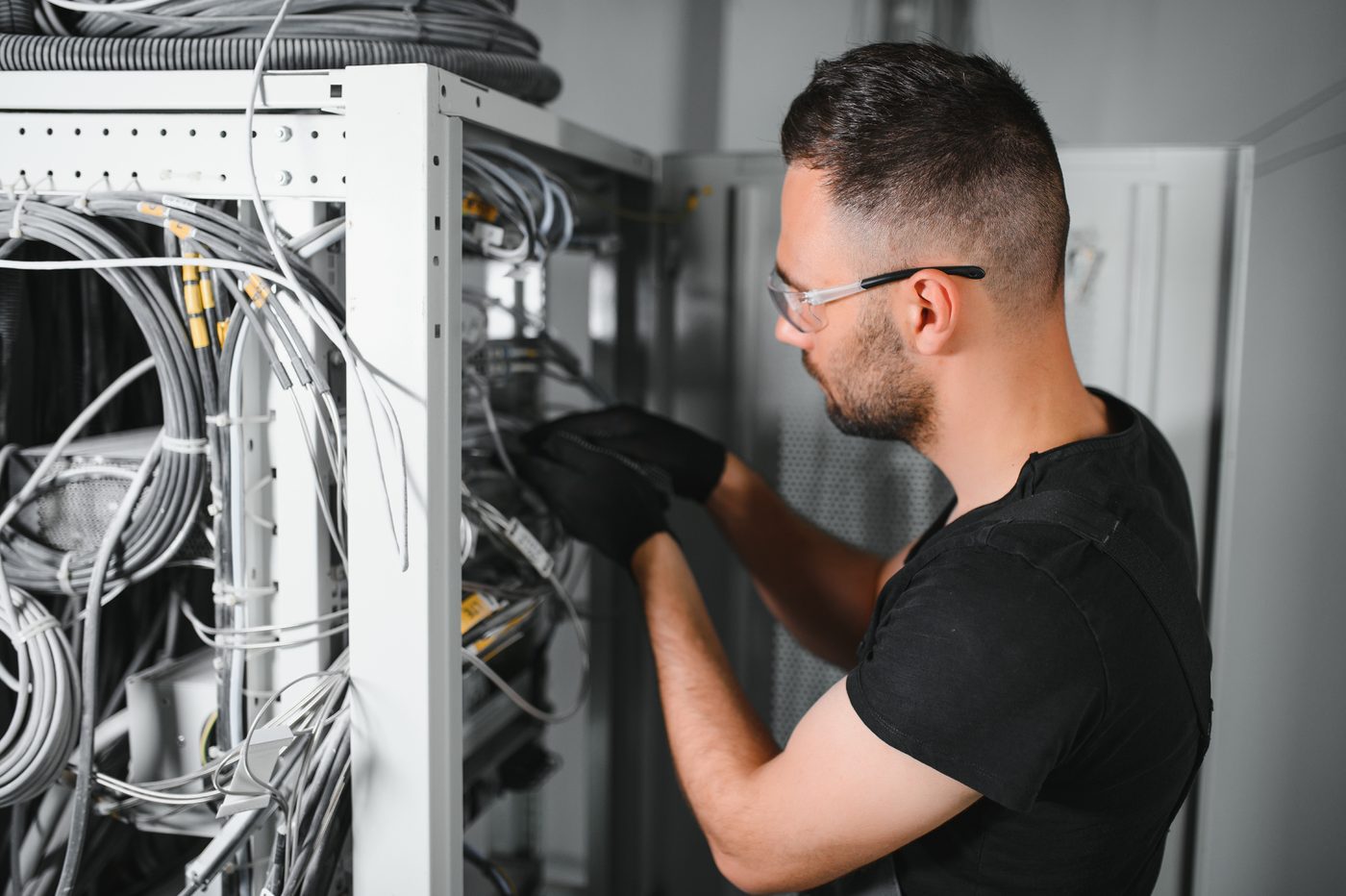 Network engineer working on a business communications rack &mdash; the resilient infrastructure behind hosted VoIP and SIP trunks.